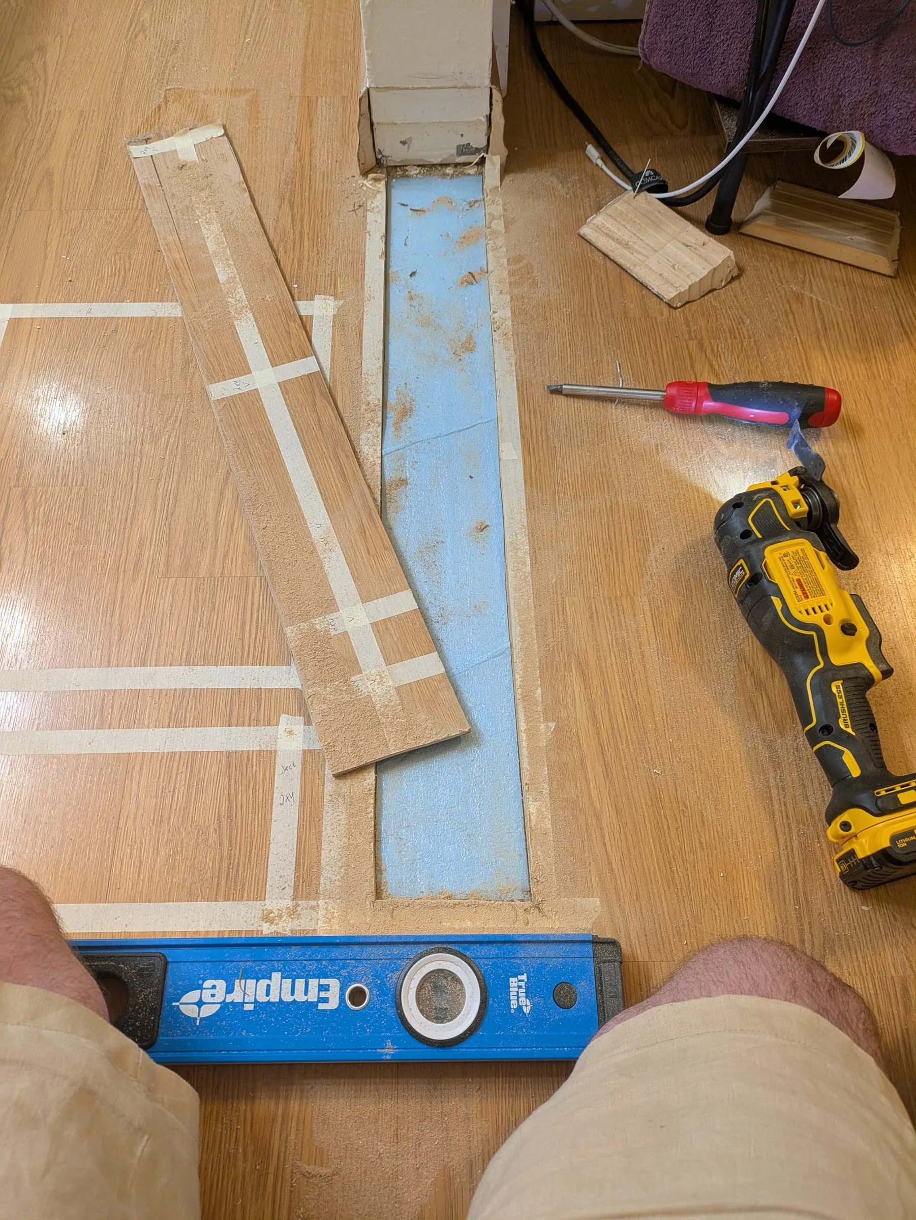 The floor marked out with tape, flooring cut away along the line of the new wall