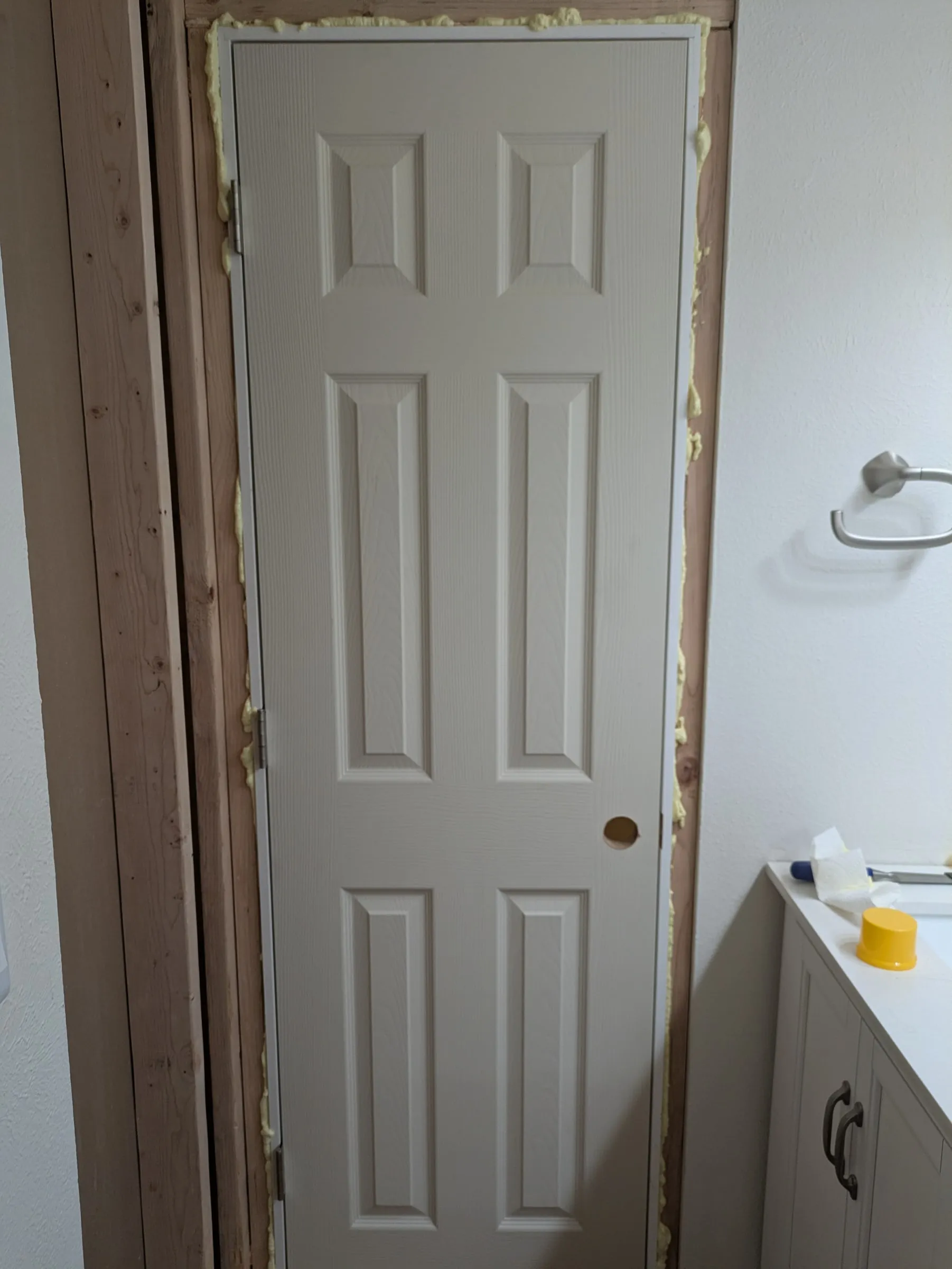 Spray foam around the door jamb from the bathroom side