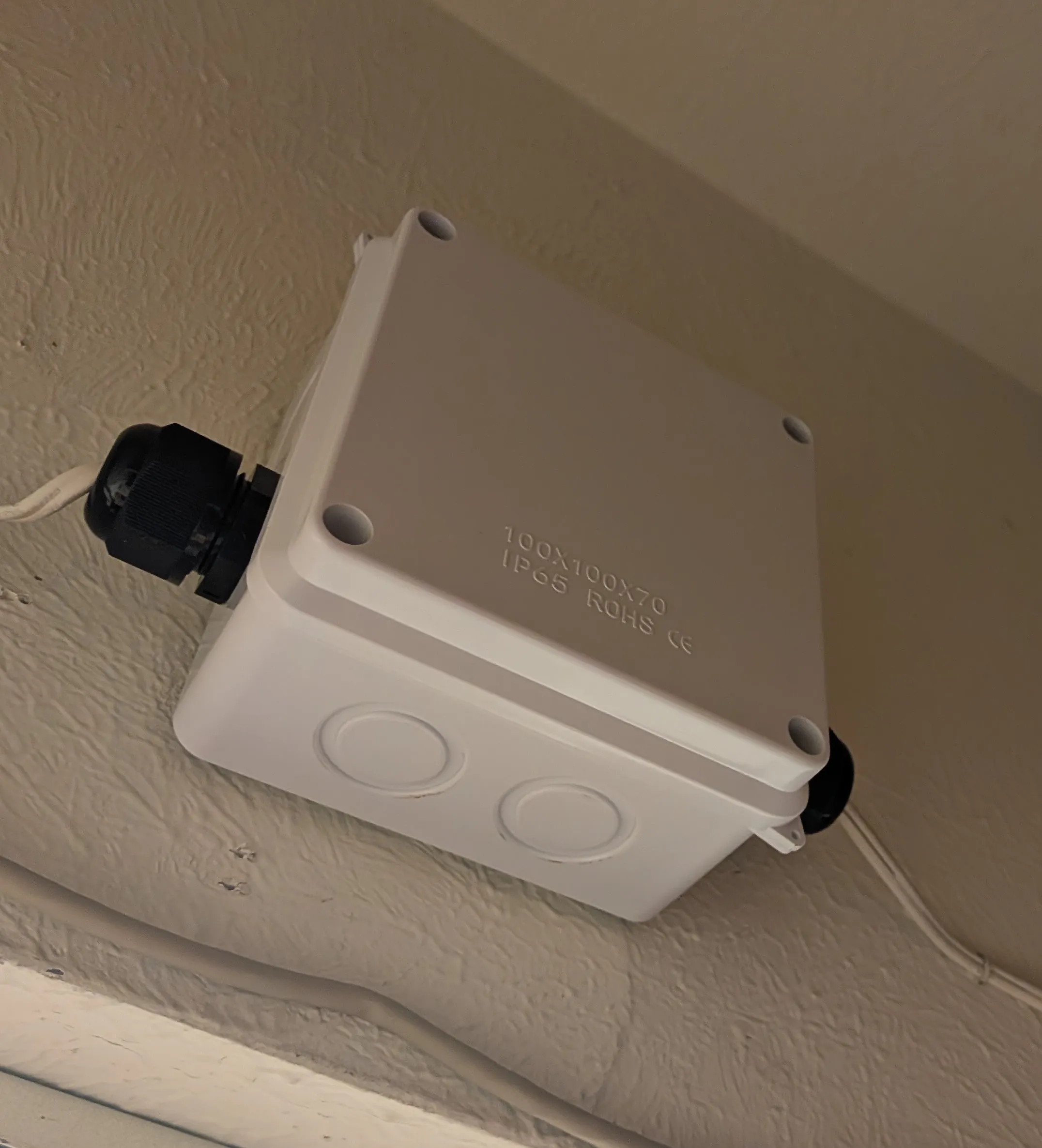 The closed IP65 junction box mounted in the corner